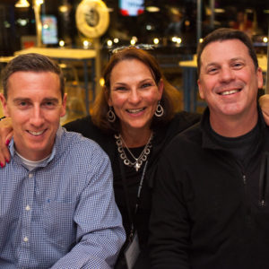 Two men and a woman posing for a photo at FINEOS Global Summit in 2017