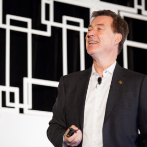 A man wearing a black suit and white shirt speaks at FINEOS Global Summit in 2017