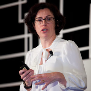 A woman wearing a white blouse speaking at FINEOS Global Summit in 2017