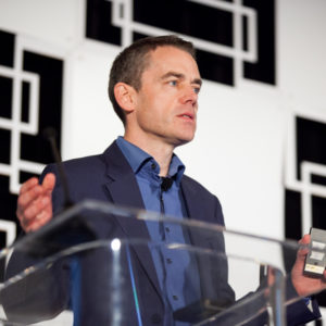 A man wearing a blue shirt and suit talking at the FINEOS Global Summit in 2017